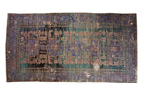 Vintage distressed Oushak runner featuring violet, teal, and charcoal medallions with heavy abrashes.