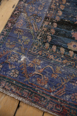 Distressed texture and vine patterns in violet, dusty copper, and teal on a vintage Oushak rug.