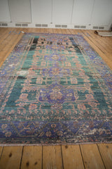 Distressed vintage Oushak runner with faded purple, teal, and copper medallion patterns, showing heavy abrashes.