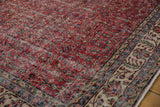 Distressed cherry red field with delicate vinery and intricate patterned beige border.