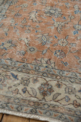 Distressed Sparta rug, worn sandalwood field, beige floral border, and visible foundation.