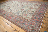 Distressed hand-knotted corner revealing pink, blue, and ivory lotus and vinery.