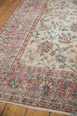 Corner of vintage distressed Sparta carpet, showing worn ivory pile, pink border, and visible foundation.