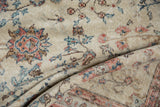 Worn pile texture and faded ivory, pink, blue floral motifs on vintage rug.