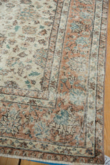 Distressed Turkish Sparta rug corner: faded ivory, apricot lotus flowers, and tinted fringe.