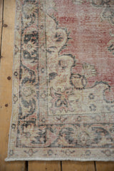Vintage Sparta rug corner with distressed dusty red, ivory pattern, visible foundation, and fringe.