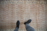 Distressed vintage Sparta rug shows allover germinating flowers in pale melon, ivory, and navy.