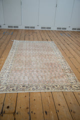 Distressed vintage Sparta rug corner with pale melon, ivory, and navy floral motifs.
