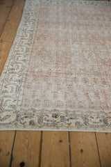 Corner view of distressed Sparta rug showing worn pale cantaloupe and ivory design.