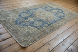 Corner view of distressed Sparta runner, featuring worn floral patterns in muted sky blue and ivory.