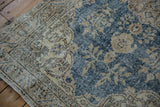 Distressed vintage Turkish Sparta rug, highlighting worn dark blue pile and ivory floral patterns.