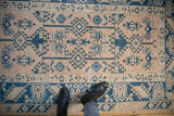 Distressed Melas rug close-up: geometric sapphire guls on dusty blush field and border.
