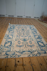 Corner of distressed Melas rug showing sapphire hook-and-latch guls and blossoming border.
