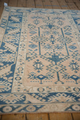 Distressed Melas rug displaying geometric guls and floral border in dusty blush, sapphire blue.