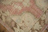 Worn pile of a Distressed Oushak rug showing soft red, ivory, and beige curvilinear motifs.