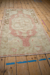 Distressed vintage Oushak rug end, showing worn pile texture and faded rose and beige colors.