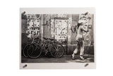 She's on the Go Black and White Photograph, woman walking past bicycles and posters.