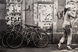 Contemporary black and white urban photograph: woman, bikes, and textured wall.