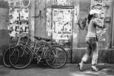 Black and white photo of two bicycles against a street wall with torn posters.