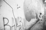 The Bambini Black and White Photograph, a child walking by an urban graffiti wall.