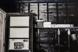 Vintage coolers and tools on a rustic wooden shelf in a black and white photograph.