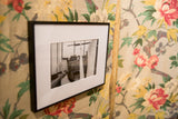 Black framed Linens black and white photograph with white mat and interior scene.
