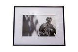The Sax Man, a framed black and white photograph of a musician in a plaid shirt playing the saxophone.