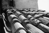 Detail of weathered terracotta tiles showing rough texture and repeating curved lines in black and white.