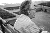 Black and white portrait shows a person chatting on a bench with a cane.