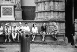 The Tourists black and white photograph of people seated on a textured stone bench.