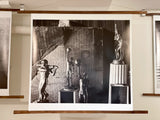 A black and white still life photograph of vintage sports trophies arranged before a textured, tattered background.