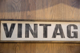 Close-up of the distressed, textured black lettering on the farm stand style vintage sign.