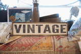 Vintage style wooden sign with black lettering shown in a rustic decor setting.