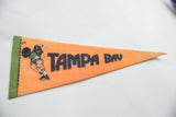 Black 'TAMPA' lettering on an orange felt vintage pennant, revealing material texture.