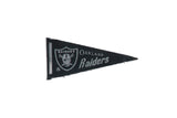 Vintage 1960s Oakland Raiders felt pennant flag with pirate logo, black and silver, 4x9 inches.