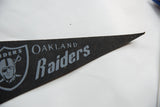 Vintage Oakland Raiders black felt pennant, showing textured surface and pinholes.