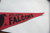 Angled close-up of the vintage pennant's pointed tip, showing the red felt texture and black letters.