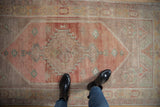 Distressed vintage Oushak runner with abrashed field and faded blush, gold, and seafoam tones.