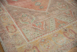 Soft, low pile of a distressed Oushak runner with faded blush and mint geometric motifs.