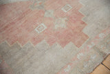 Distressed Oushak rug detail: geometric stepped pattern in dusty rose and time-softened beige.