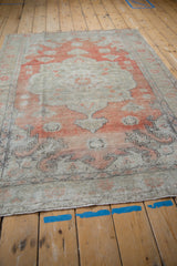 Distressed Oushak rug detail with faded brick red and neutral germinating plant spandrels.