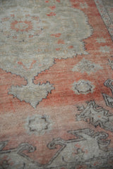 Distressed Oushak rug texture detail with faded brick red and silver leaf patterns.