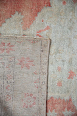 Faded brick red pile of distressed vintage Oushak rug with hand-knotted beige reverse.