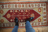 Overhead view showing the scale of a vintage distressed Oushak rug runner with a red floral medallion.