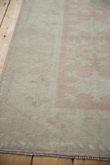 Distressed Oushak rug pile texture, with muted dusty rose motifs and intact selvage.