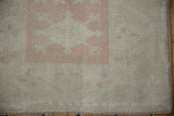 Distressed Oushak rug corner detail, dusty pink guls, ivory field, original selvage, and even wear.