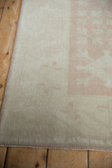 Distressed vintage Oushak rug runner side, showing original selvage, dusty pink pattern, and even pile wear.
