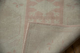 Distressed vintage Oushak runner showing soft pink pattern, intact selvage, and tightly woven back.