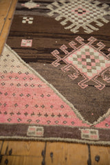 Distressed Kars rug runner, featuring geometric medallions and hook motifs in pink and brown.