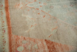 Distressed Turkish Oushak rug corner showing sun-faded sea foam and rust patterns.